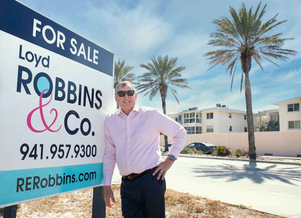 Loyd Robbins Standing by Sign